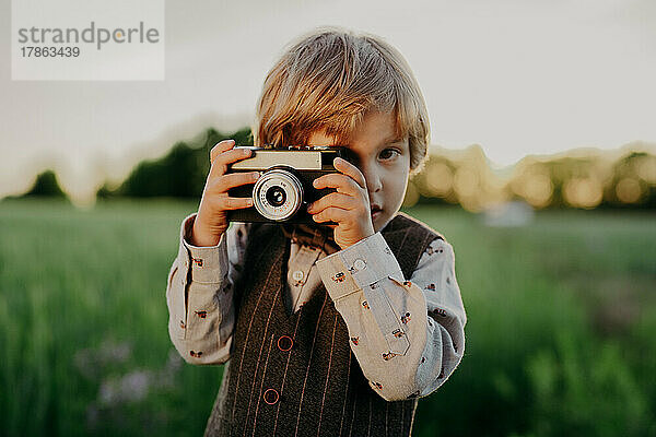Hipster kleiner Junge mit Vintage-Kamera im Freien. Kind im Kostüm