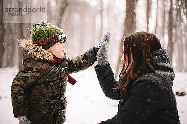 Mutter und Sohn geben im Winter im Park High Five