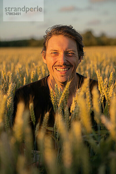 Attraktiver weißer Mann lächelt in die Kamera  beleuchtet vom Sonnenuntergangslicht