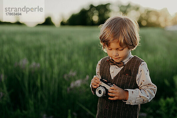 Hipster kleiner Junge mit Vintage-Kamera im Freien. Kind im Kostüm