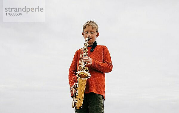 Junge spielt glücklich Saxophon im Freien