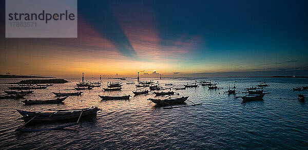 Sonnenuntergang in der Bucht von Jimbaran auf Bali mit Fischerbooten