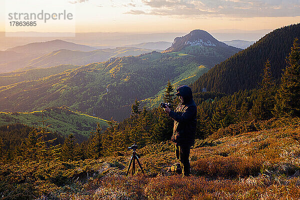 Bergsteiger fotografiert die Aussicht bei Sonnenuntergang mit der Kamera