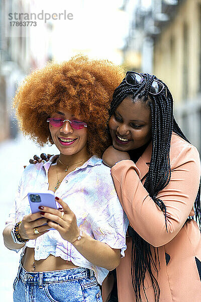 Lächelnde Freunde  die mit ihrem Smartphone schauen
