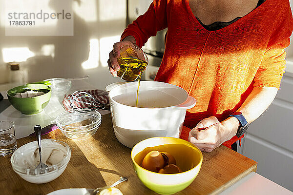 Frau gießt Öl in eine Schüssel in der Küche.