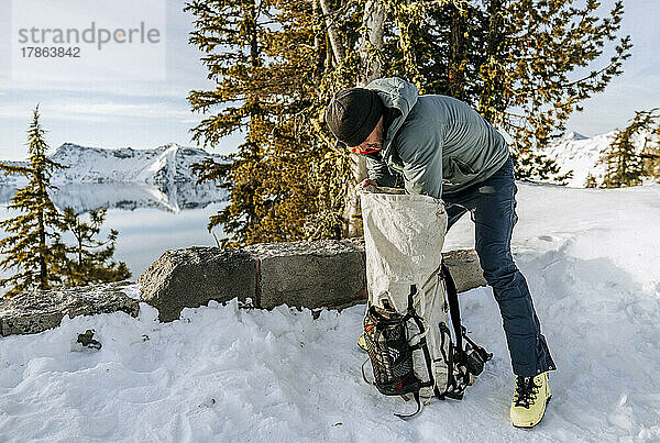 Skifahrer lädt im Winter beim Camping in der Nähe des Crater Lake seinen Rucksack.