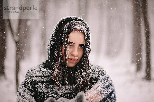Porträt einer jungen Frau  bedeckt mit Schnee  die im Winter im Park steht