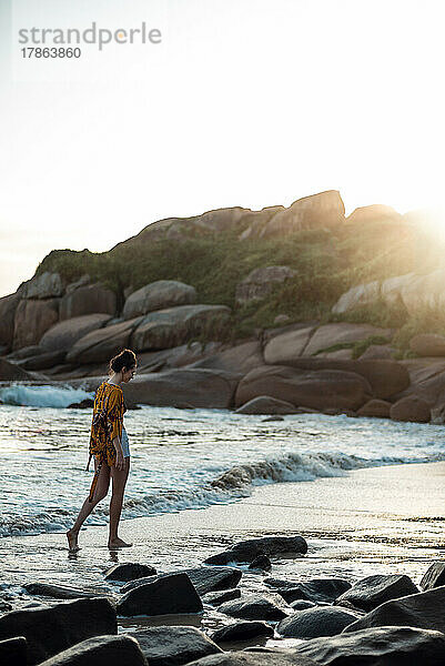 Junge Frau spaziert am einsamen Strand