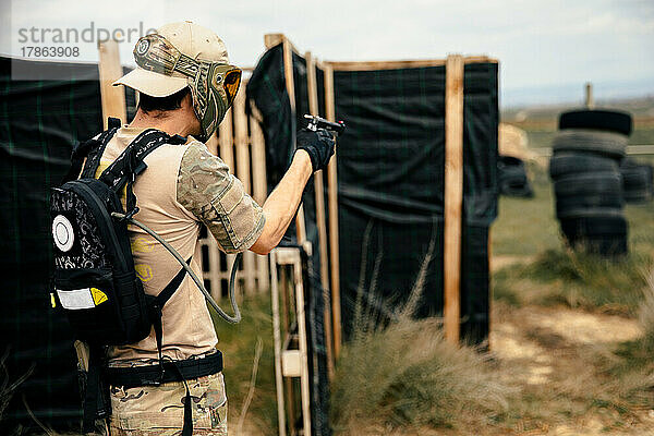 Soldat im Tarnanzug hält während eines Airsoft-Kampfes eine Waffe