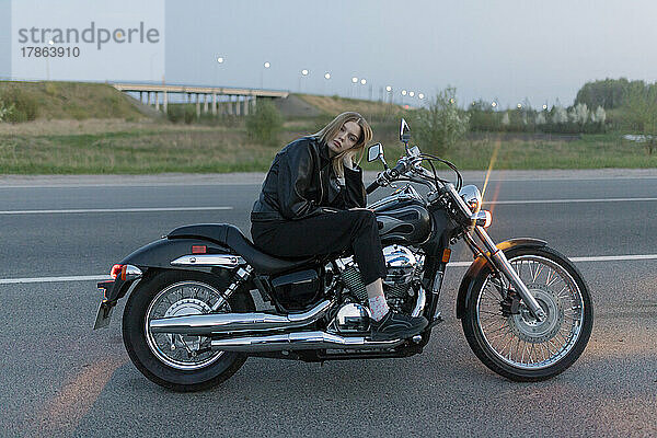 Blonde Frau sitzt allein auf einem Motorrad