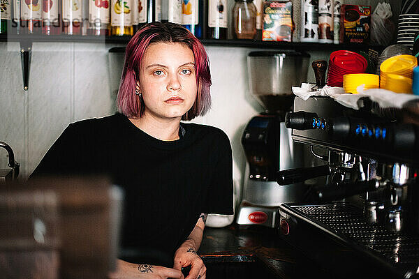 Junge Barista sitzt an der Kaffeemaschine im Café