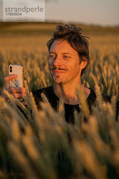 Junger  fröhlicher  aufgeregter Mann mit T-Shirt steht im Weizenfeld