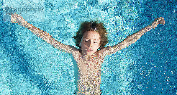 Junge im Schwimmbad mit geschlossenen Augen  Ansicht von oben