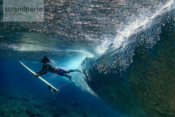 Unterwasseransicht eines männlichen Surfers  der einen Ententauchgang macht
