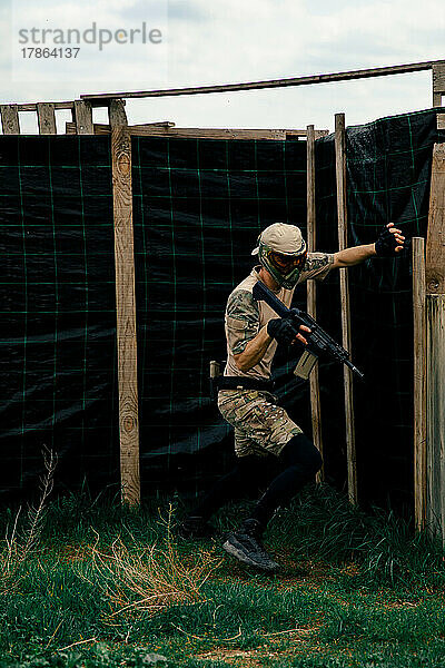 Soldat im Tarnanzug hält während eines Airsoft-Kampfes eine Waffe