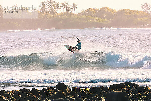 Männlicher Surfer auf einer Welle am Morgen