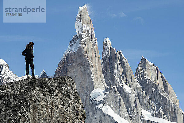 Die Silhouette eines Wanderers zeichnet sich vor den gewaltigen Gipfeln des Cerro Torre ab