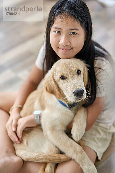 Porträt eines Mädchens mit einem Golden Retriever-Welpen in der Umarmung