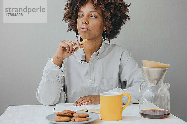 Eine mürrische afroamerikanische Frau frühstückt und schreibt ein Tagebuch.