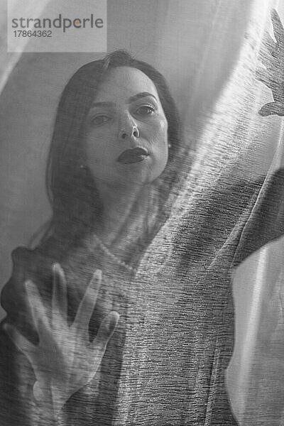 Frau blickt durch transparenten  schwarz-weißen Stoff