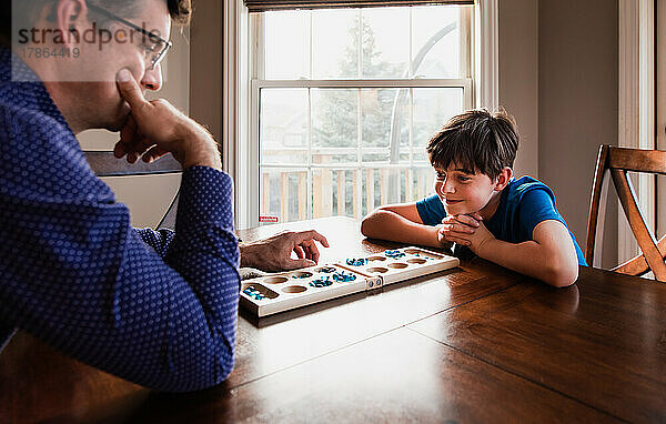 Junge und sein Vater haben Spaß daran  zu Hause gemeinsam ein Spiel zu spielen.