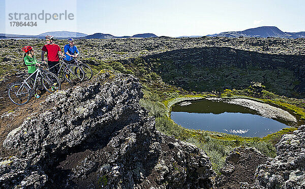 Drei Freunde erkunden mit ihren Mountainbikes einen Vulkankrater