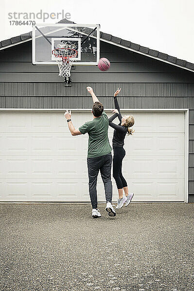 Vater und Tochter üben Basketball in der Einfahrt zu Hause