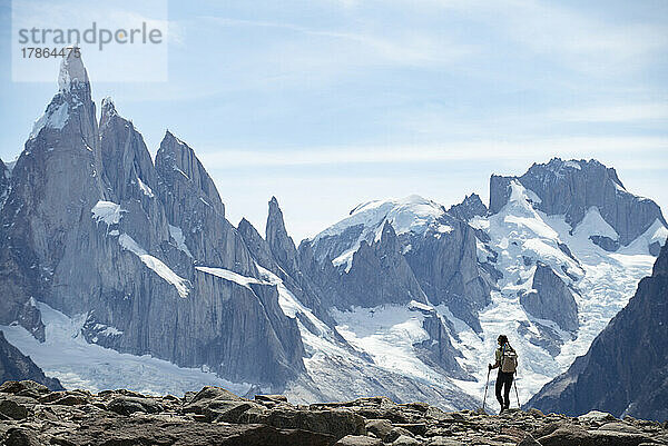 Die Silhouette eines Wanderers zeichnet sich vor den gewaltigen Gipfeln des Cerro Torre ab