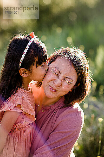 Nahaufnahme einer Tochter  die ihre Mutter bei Sonnenuntergang in San Diego küsst