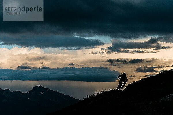 Mountainbiker kurven auf der Bergrückenlinie im Loomy Alpine Vista