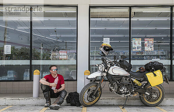 Mann macht eine Pause auf einer Motorradtour in Thailand