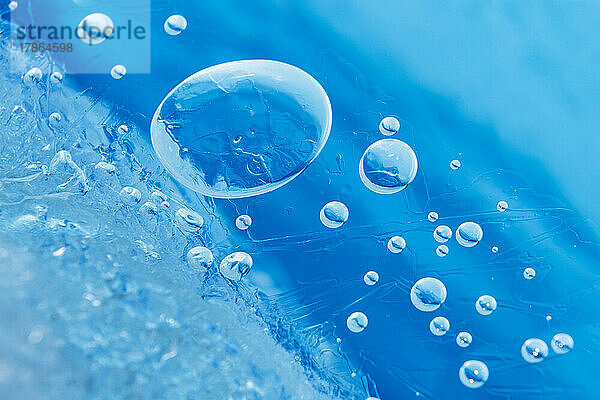 Kleine Blasen  die unter dem Eis im strahlend blauen Wasser eingeschlossen sind