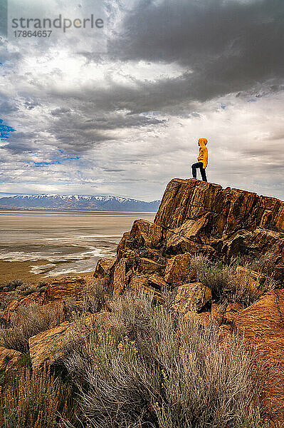 ein Junge  der auf einem hohen Felsen steht und über einen ausgetrockneten Seegrund in Utah blickt