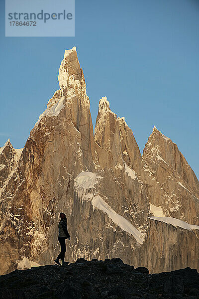 Die Silhouette eines Wanderers zeichnet sich vor den gewaltigen Gipfeln des Cerro Torre ab