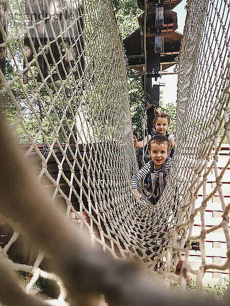 Fröhliche Kinder in einem Netz in einem Seilpark