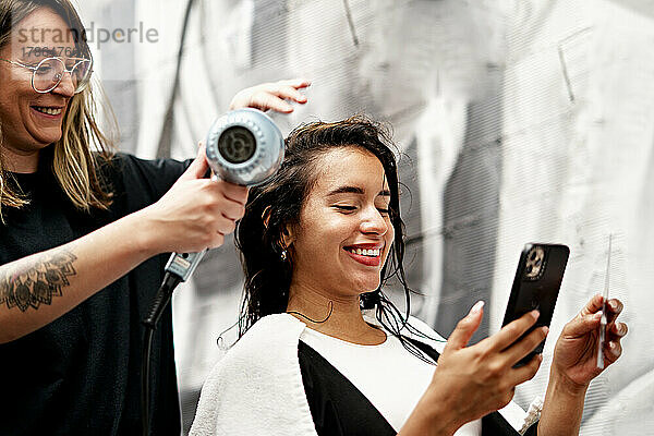 Friseur trocknet Haare eines fröhlichen Kunden