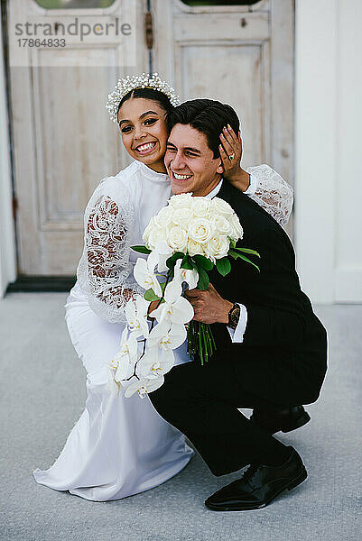 Gemischtrassige Braut und Bräutigam umarmen sich und haben ein breites  glückliches Lächeln