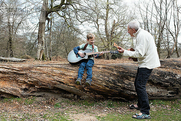 Großvater bringt seinem Enkel im Urlaub das Gitarrespielen bei