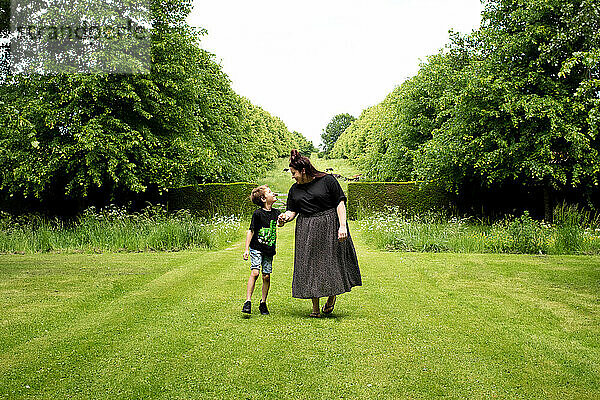 Mutter und Sohn gehen glücklich durch einen wunderschönen englischen Garten