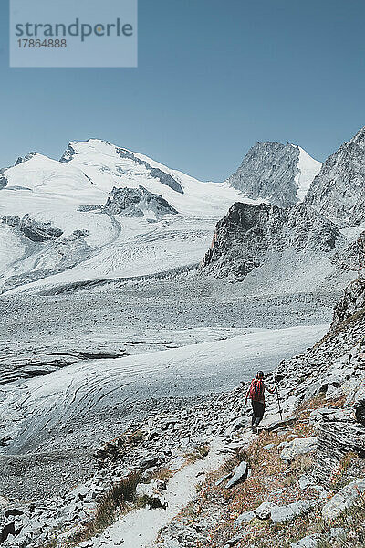Vertikales Bild eines Wanderers von hinten  der auf Gletscher und Gipfel zugeht