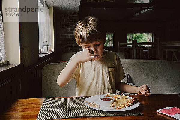 Netter gesunder Vorschulkinderjunge isst im Café.
