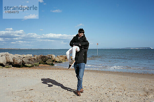 Vater und Sohn spielen glücklich am Strand und haben Spaß