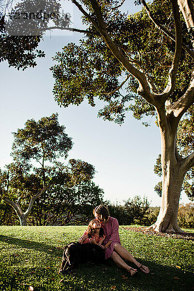 Mutter und Tochter posieren unter einem Baum mit Hund in San Diego