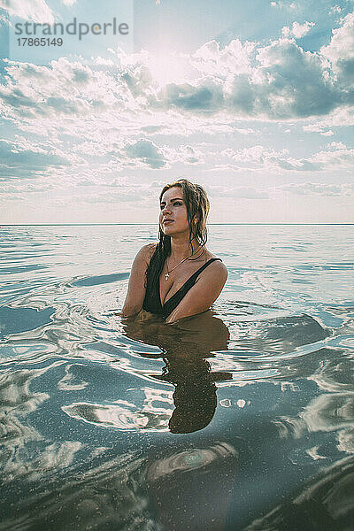 Elegante Frau sitzt im Wasser. Das Konzept der Einheit mit der Natur.
