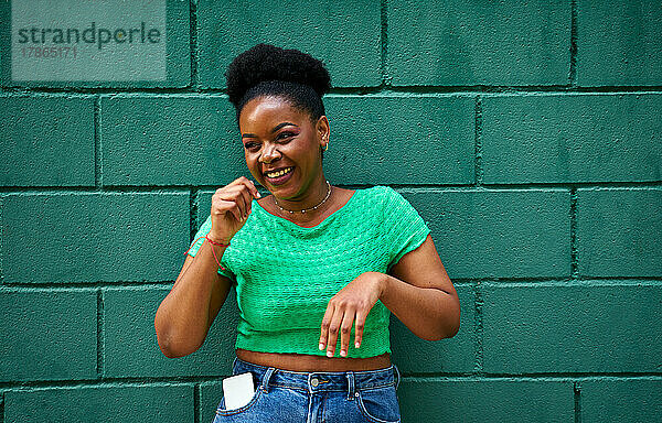 Afroamerikanische Frau lächelt auf grüner Wand