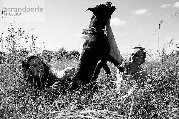 Lesbisches Paar spielt mit seinem Hund beim Spaziergang auf einem Feld