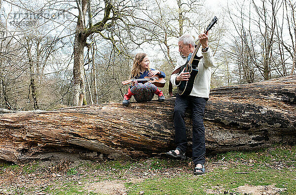 Großvater spielt Gitarre mit seiner Enkelin im Wald