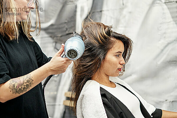 Friseur trocknet Haare eines fröhlichen Kunden