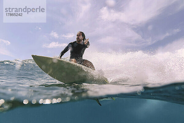 Männlicher Surfer auf einer Welle an einem sonnigen Tag