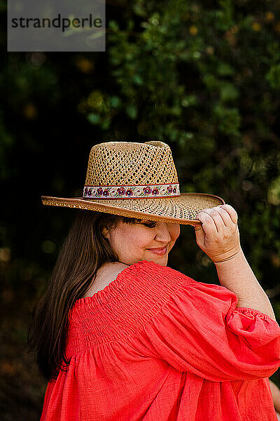 Plus-Size-Model trägt schulterfreie Bluse und Hut in San Diego
